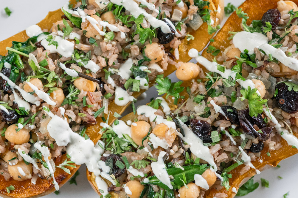 Vegan stuffed butternut squash with chickpeas, wild rice and cranberries. Drizzled with cashew cream.