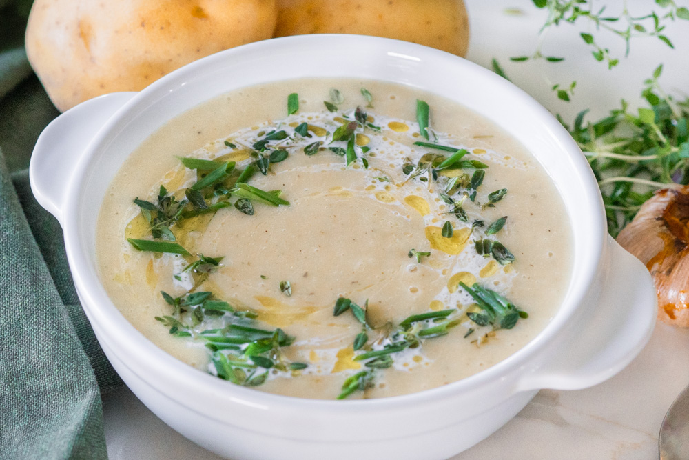 Roasted garlic potato leek soup in a white bowl. 
