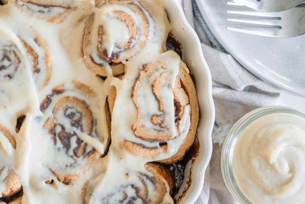 Gluten-free and vegan Maple Frosted Cinnamon Buns in a white dish from above.