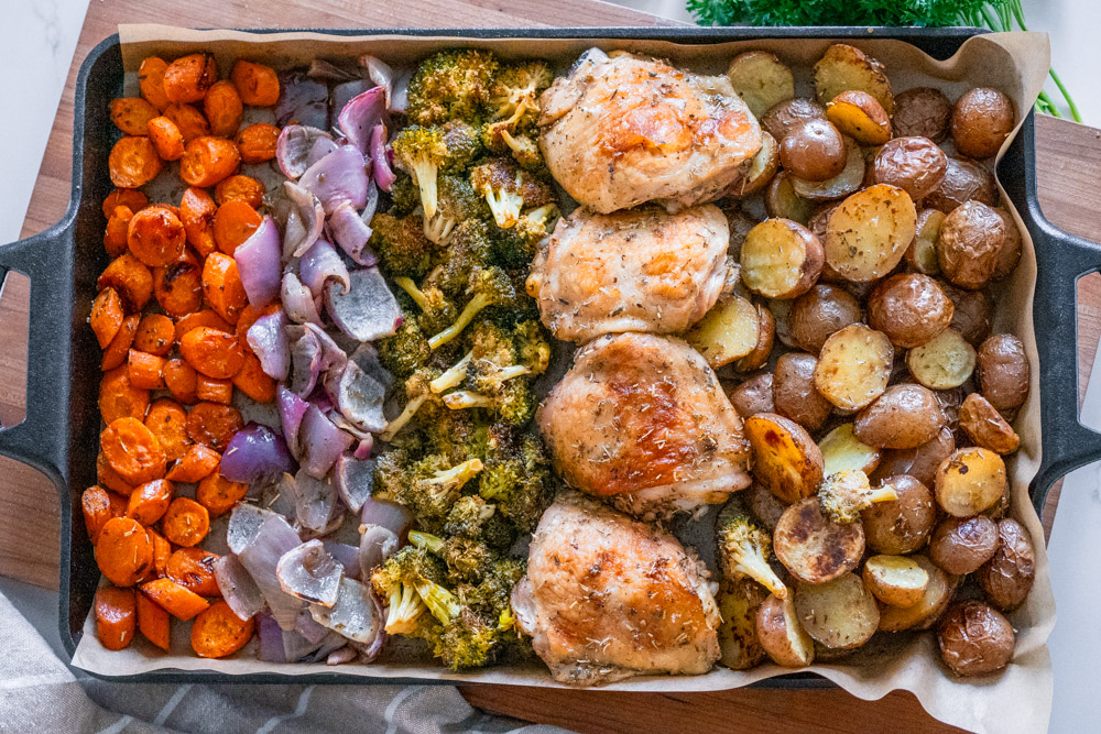 Sheet pan chicken & veggies on a wooden cutting board.