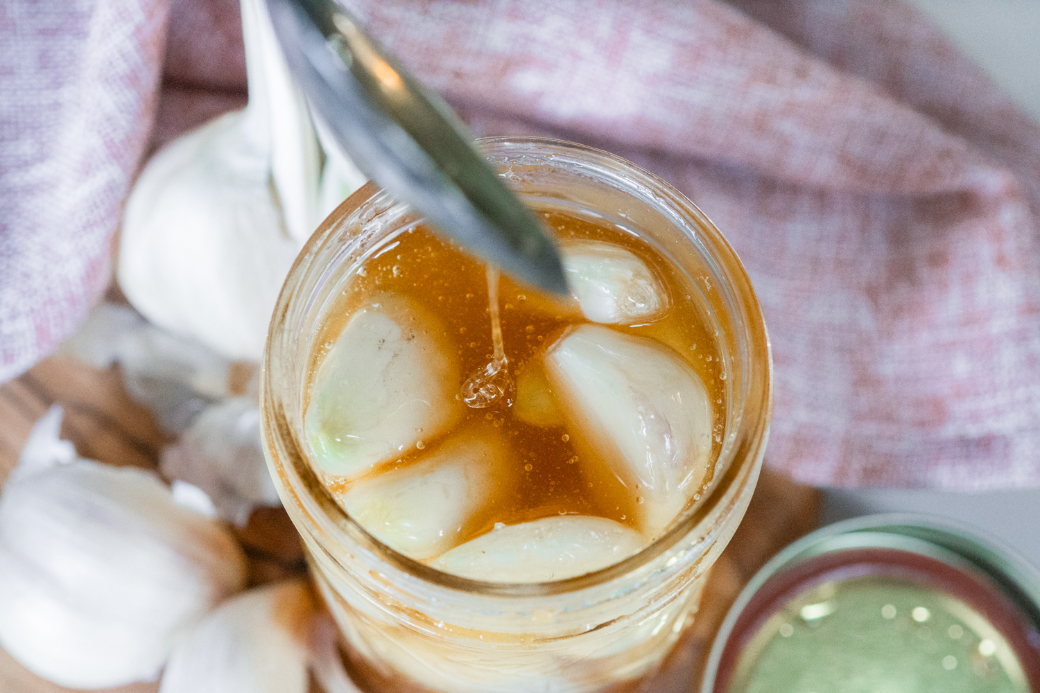 Glass mason jar filled with fermented honey garlic on a counter.