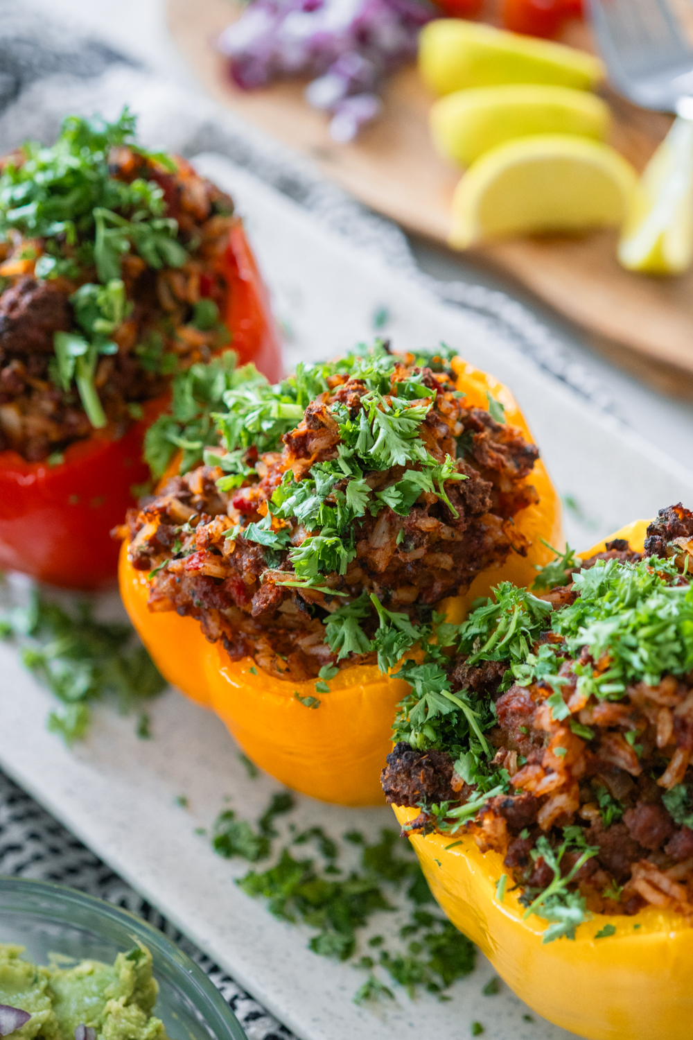 Classic chilli stuffed peppers stacked together on a white dish. Sprinkled with parsley.
