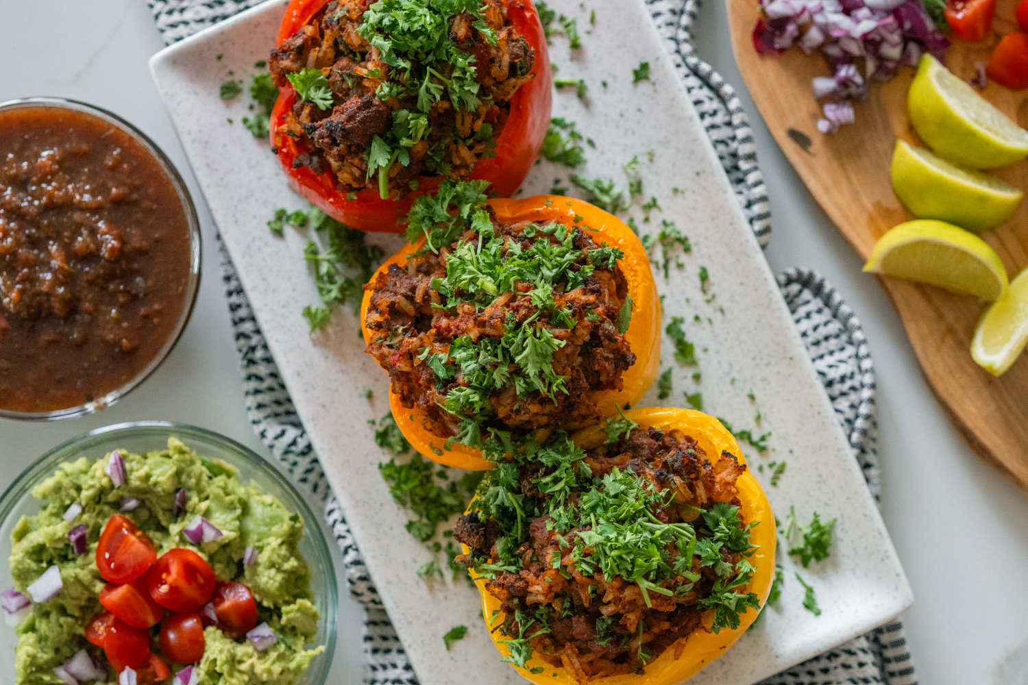 Classic chilli stuffed peppers stacked together on a white dish. Sprinkled with parsley.