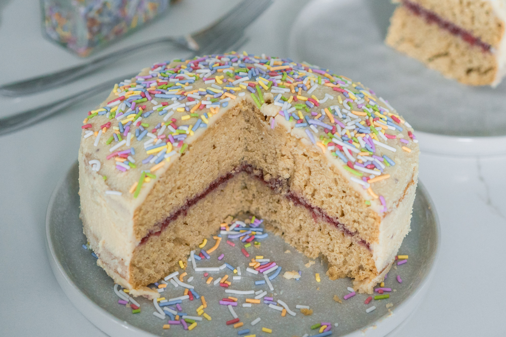 Gluten-free vanilla birthday cake on a plate with naturally dyed sprinkles.
