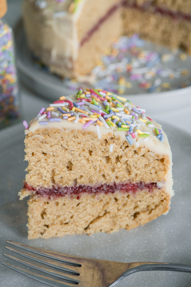Gluten-free vanilla birthday cake on a plate with naturally dyed sprinkles.