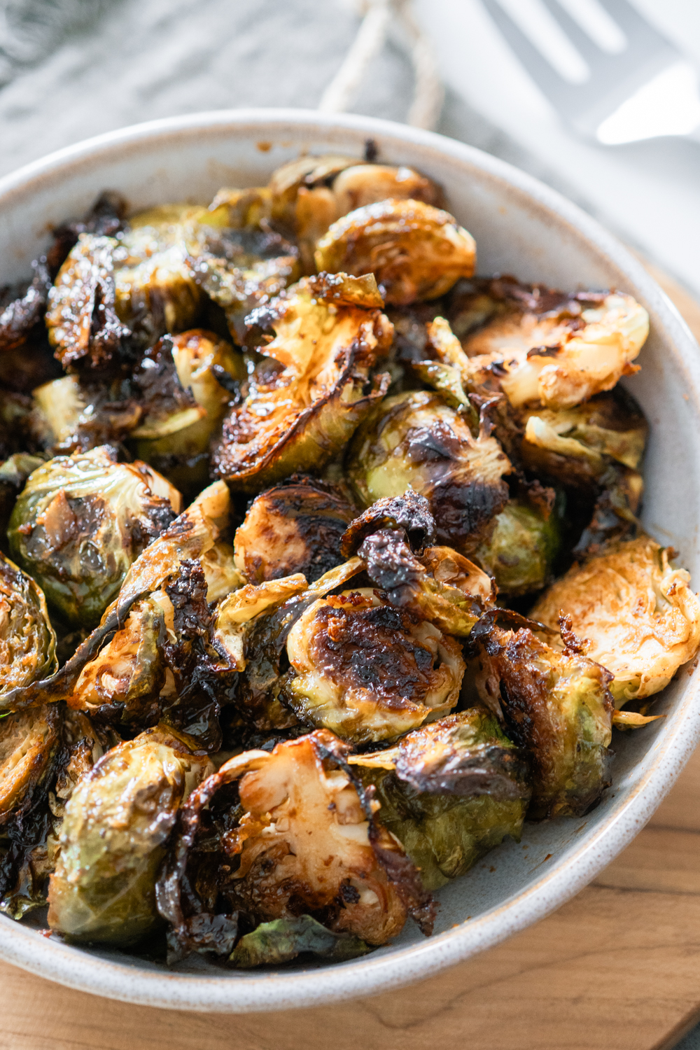 Caramelized Balsamic Brussels Sprouts in a white bowl on a cutting board.