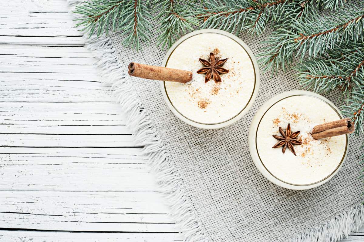 Homemade eggnog in glasses with star anise and cinnamon stick.