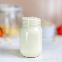 Creamy cashew alfredo sauce in a mason jar on a white table.