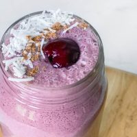 The Hormone Smoothie in a mason jar topped with a cherry, coconut and cinnamon.