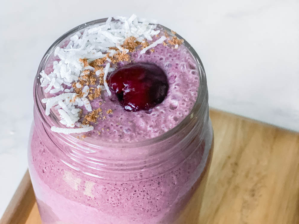 The Hormone Smoothie in a mason jar topped with a cherry, coconut and cinnamon.