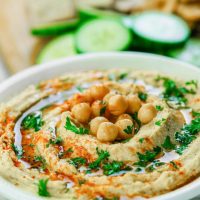 Easy homemade hummus in a white bowl sprinkled with paprika and parsley