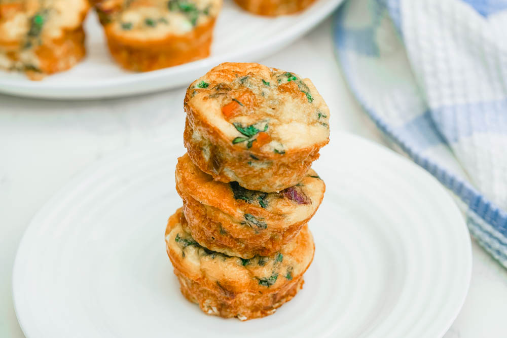 Three fall harvest egg muffins stacked on a white plate.