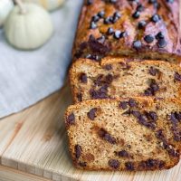 Paleo pumpkin bread with chocolate chips sliced on a wood cutting board.