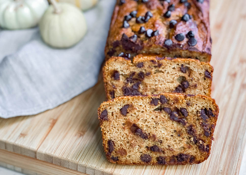 Paleo pumpkin bread with chocolate chips sliced on a wood cutting board.
