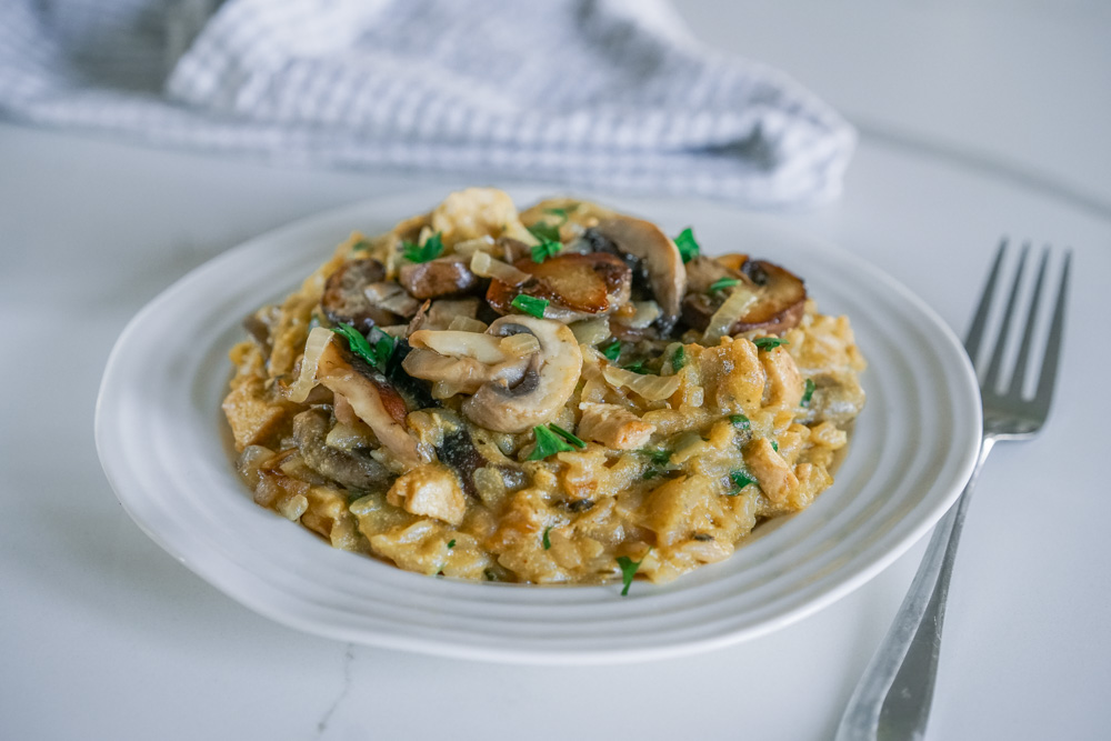 Delicious chicken and mushroom risotto with fresh parsley on a white plate.