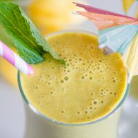 Anti-inflammatory sunshine smoothie with pineapple, turmeric and ginger in a tall glass with cocktail umbrella.