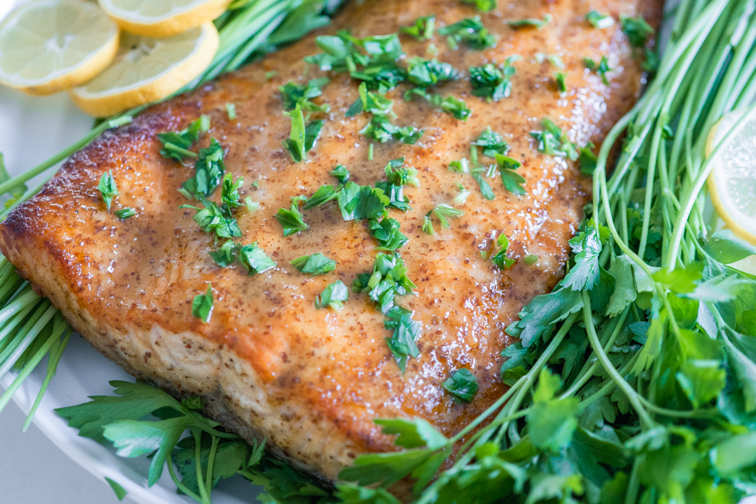 Honey dijon salmon on a bed of fresh parsley sprinkled with herbs.