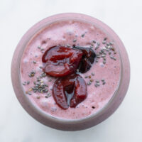 Cherry bomb smoothie in a glass cup. Topped with halved cherries and sprinkled with chia seeds.