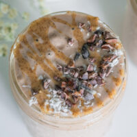 Cacao almond butter smoothie in a mason jar with cacao nibs and coconut sprinkled on top.