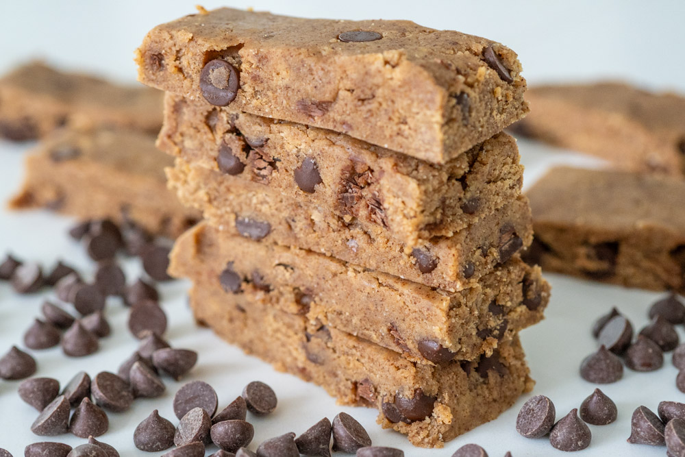 Cookie dough protein bars cut in rectangles and stacked on top of each other.