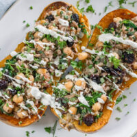 Vegan stuffed butternut squash with chickpeas, wild rice and cranberries. Drizzled with cashew cream.