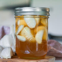 Glass mason jar filled with fermented honey garlic on a counter.
