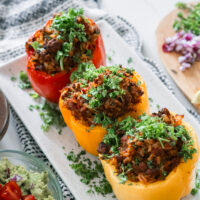 Classic chilli stuffed peppers stacked together on a white dish. Sprinkled with parsley.