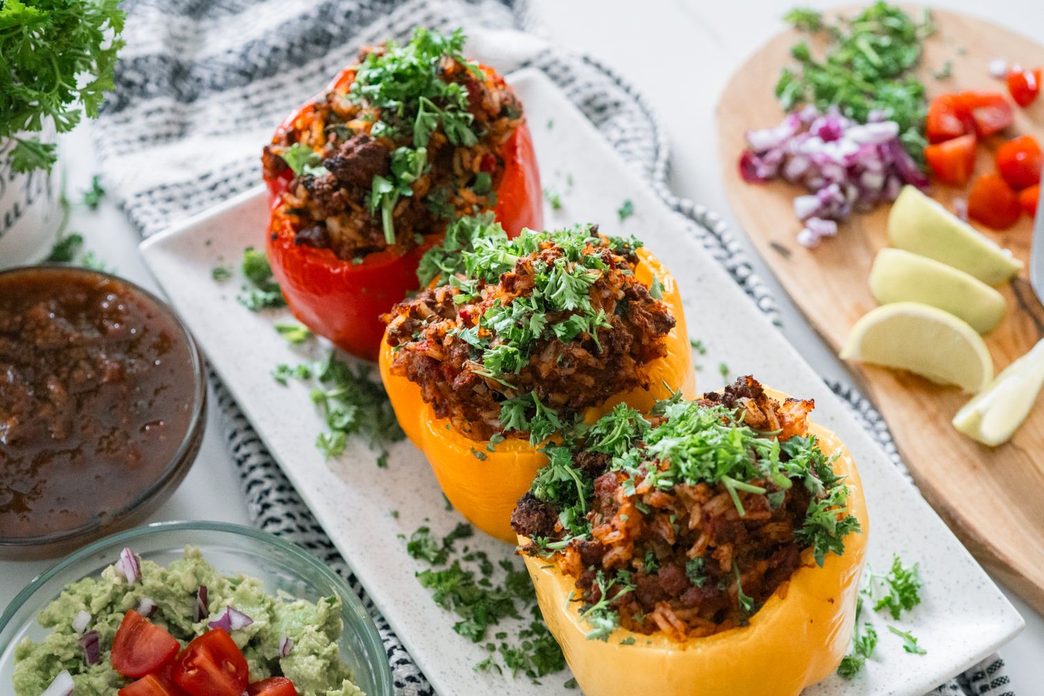 Classic chilli stuffed peppers stacked together on a white dish. Sprinkled with parsley.