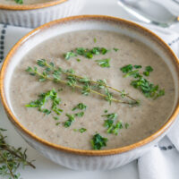Vegan cream of mushroom soup in a bowel with thyme.