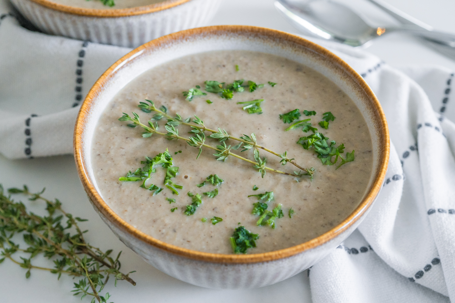 Vegan cream of mushroom soup in a bowel with thyme.