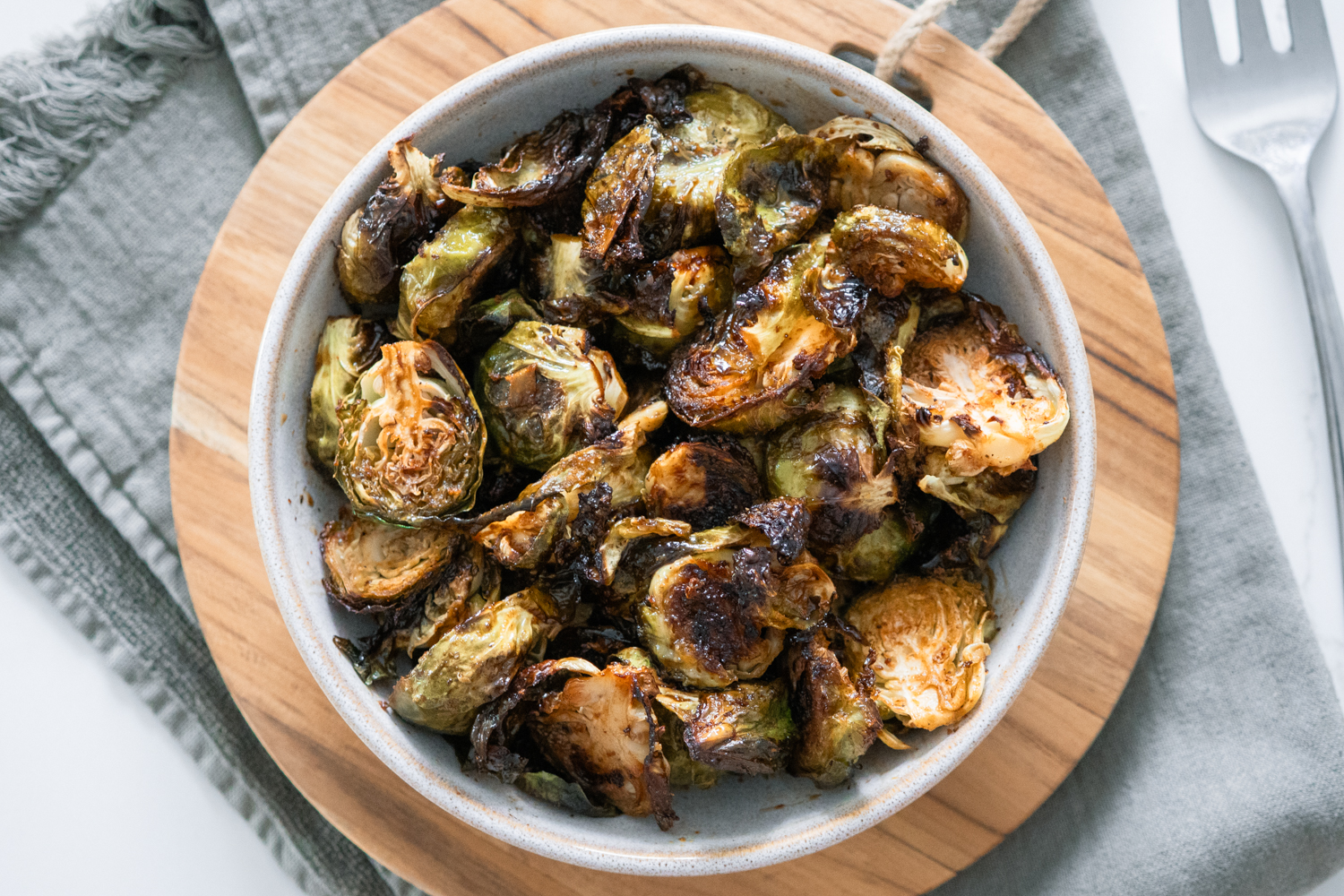Caramelized Balsamic Brussels Sprouts in a white bowl on a cutting board.